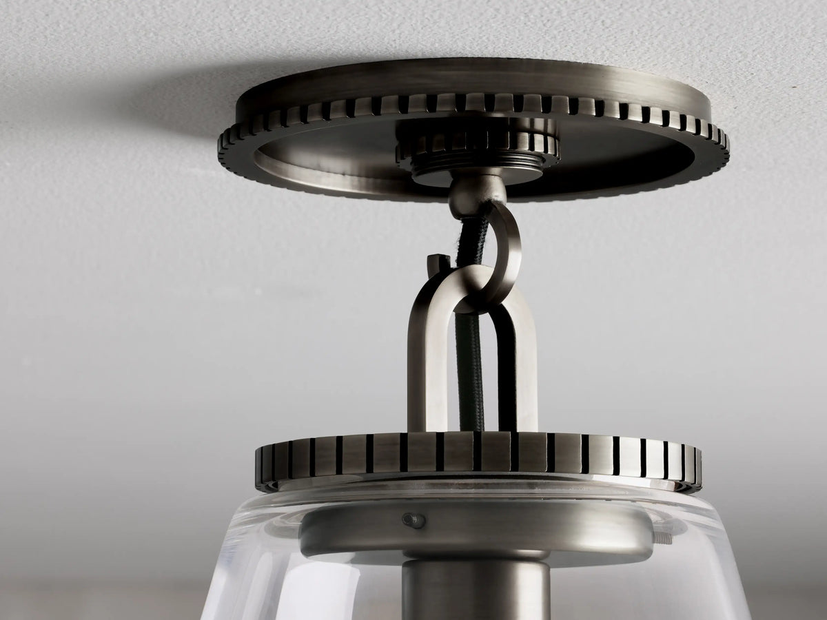 Wescott Cone Flush Mount with bronze finish, clear glass shade, and metal canopy with detailed gear-like edges on white ceiling.
