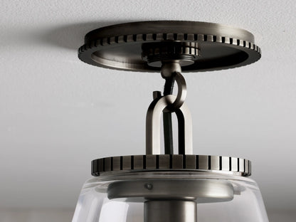 Wescott Cone Flush Mount with bronze finish, clear glass shade, and metal canopy with detailed gear-like edges on white ceiling.