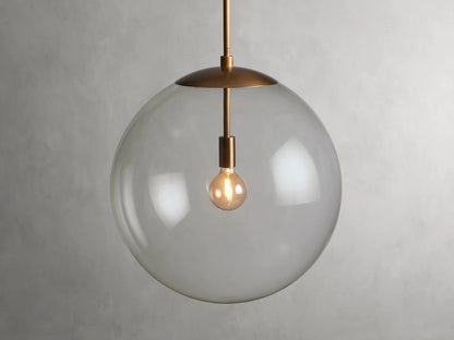 A clear glass globe pendant with a brass finish rod and fixture, showcasing a visible bulb inside, hung against a plain background.