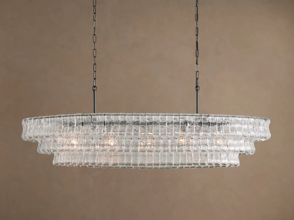 Ghiaccio Oval Chandelier: clear textured glass in tiered wavy segments, suspended by dark chains, with a soft inner glow.