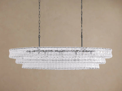 Ghiaccio Oval Chandelier: clear textured glass in tiered wavy segments, suspended by dark chains, with a soft inner glow.