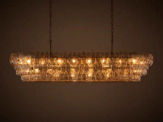 Ghiaccio Oval Chandelier: clear textured glass in tiered wavy segments, suspended by dark chains, with a soft inner glow.