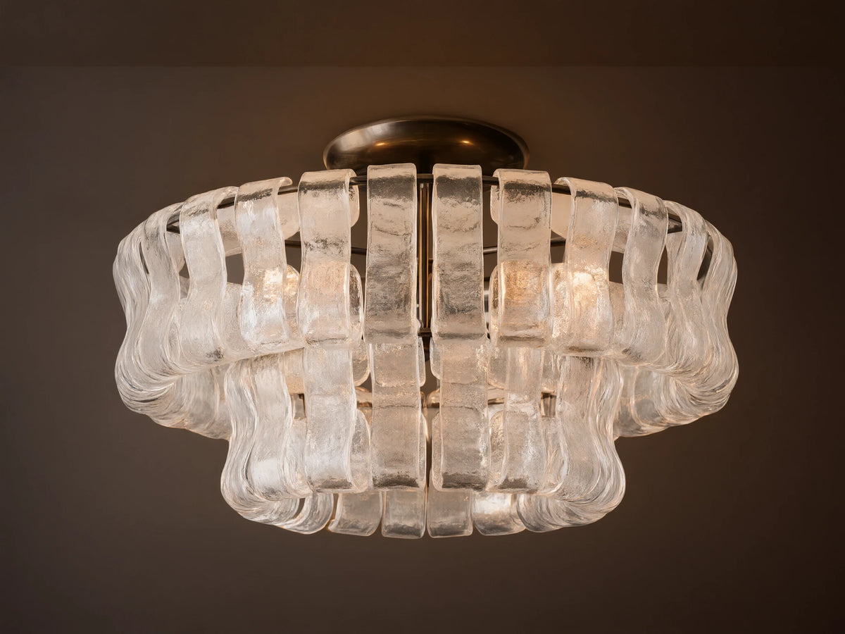 Ghiaccio Flush Mount with a dark steel base and layered, textured clear glass pieces forming a wavy, sculptural design. Soft glow.