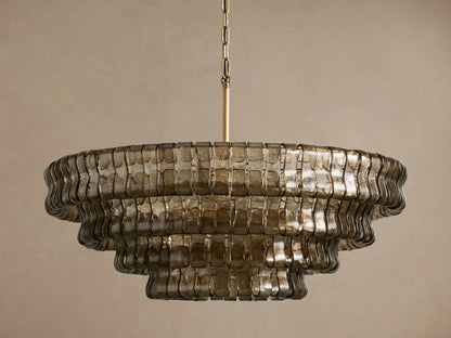 Ghiaccio Round Chandelier with three tiers of rippled, bronze-toned glass, hanging from a gold chain on a light background.