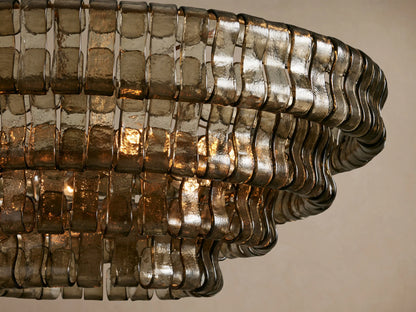 Close-up of Ghiaccio Round Chandelier with textured smoky gray curved glass strips, illuminated by warm internal lights.