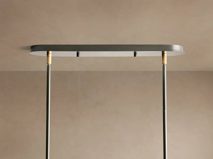 Close-up of Daphne Linear Chandelier showing white fabric shades with black trim, connected by a black rod with bronze accent.