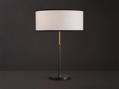Daphne Table Lamp with white linen shade, black trim, dark bronze finish, and brass accent, on a wooden table.