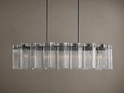 Delsie Oval Chandelier: clear ribbed glass cylinders hang from a dark oval frame, suspended by two rods against a wall.
