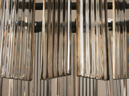 Delsie Oval Chandelier close-up: vertical ribbed glass panels in champagne tones, shimmering, with dark structural elements.