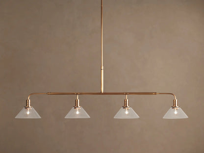 Theron Linear Chandelier: horizontal brass bar, 4 lit bulbs inside milk glass cone shades, hanging against brown wall.