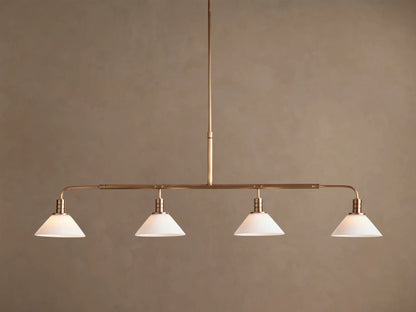 Theron Linear Chandelier with four milk glass cones on a horizontal brass bar, suspended against a warm brown wall.
