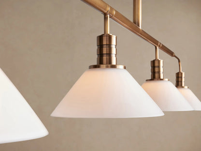 Theron Linear Chandelier, brass finish, four white conical milk glass shades on a horizontal bar, hanging from a vertical rod.