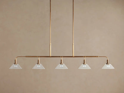 Brass Theron Linear Chandelier, 5 inverted milk glass cone shades with lit bulbs, suspended from vertical rods.