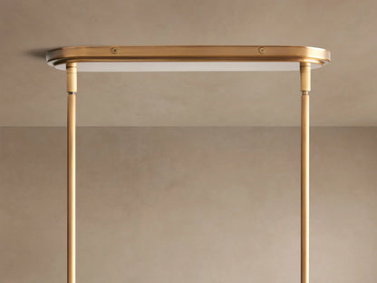 Close-up of a brass-finished Theron Linear Chandelier with clear cone glass shades and glowing bulbs against a light wall.