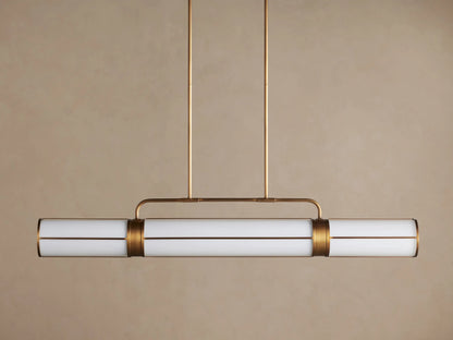 Remming Linear Chandelier: Three glowing milk glass cylinders in a burnished brass frame, suspended from above.