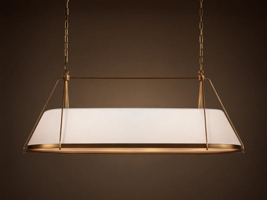 Shelton Linear Chandelier with burnished brass frame & illuminated tapered white linen shade, hanging from chains.