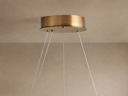 Halo-shaped chandelier with a warm glow, crafted from Spanish alabaster stone. Features brass accents and steel cables for mounting.