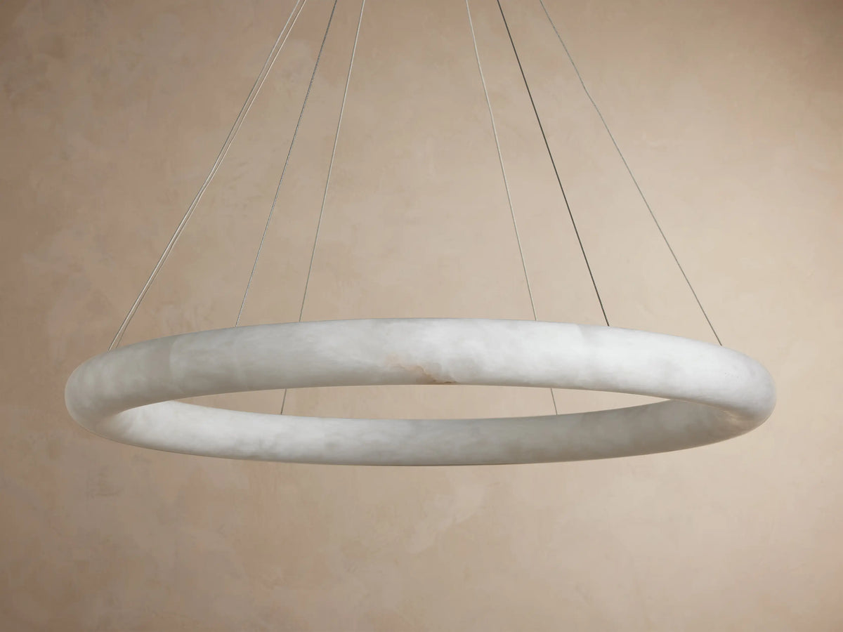 Glowing Halima Halo Chandelier, a large circular light fixture crafted from veined alabaster and suspended by thin cables.