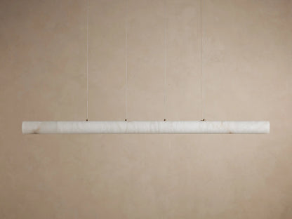 Halima Linear Chandelier with alabaster stone finish, suspended by steel cables, glowing warmly on a plain background.