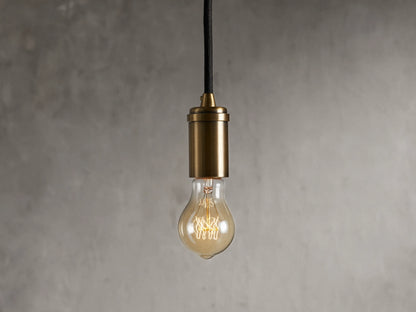 Ohlson Brass Swag Pendant with a brass-plated finish, hanging against a textured gray background.