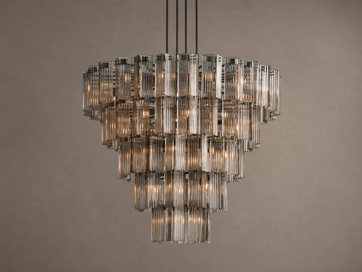 Delsie Round Chandelier, tiered with many illuminated clear fluted glass rods, suspended against a warm brown wall.