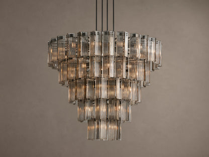 Delsie Round Chandelier, tiered with many illuminated clear fluted glass rods, suspended against a warm brown wall.
