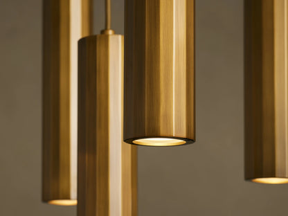 Four cylindrical bronze pendant lights with a brushed texture, hanging from the ceiling against a neutral background. The lights are illuminated.