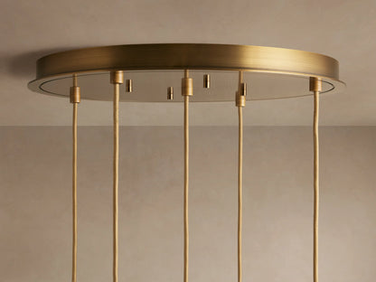 Ceiling light fixture with a round, brushed brass base and multiple hanging cords. The fixture is mounted on a light-colored ceiling.