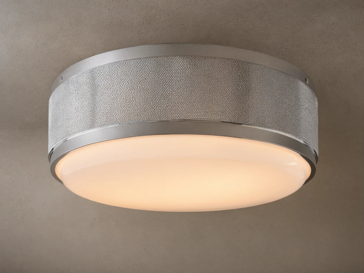 Round ceiling light with a brushed metal frame and frosted glass diffuser. Soft warm glow, mounted on a neutral-colored ceiling.