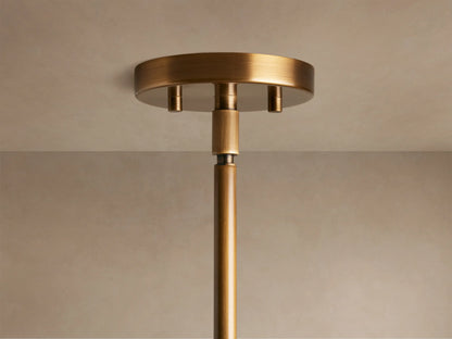 Bronze pendant light fixture with a frosted glass shade, featuring a spherical design, casting a warm glow against a soft brown background.