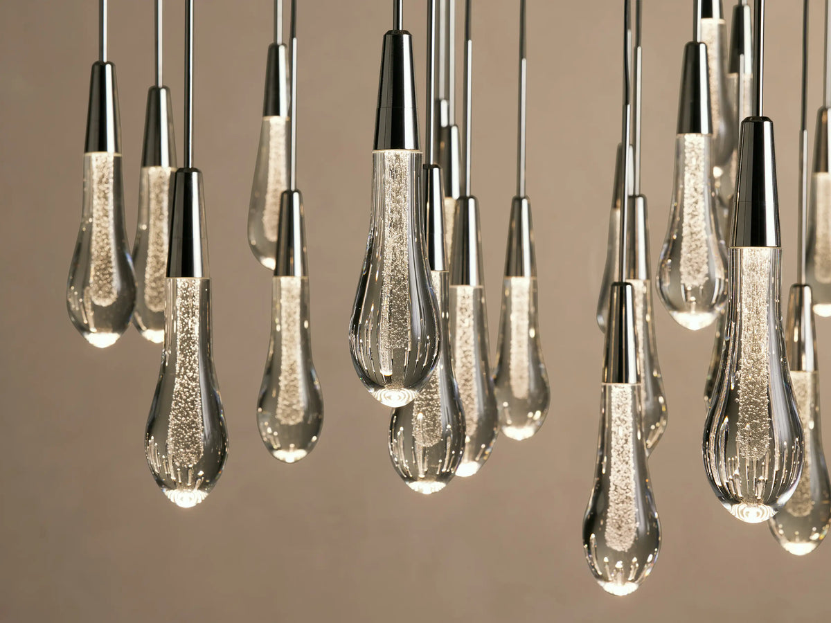 Alt text: Soltaire Round Chandelier with multiple elongated, teardrop-shaped glass bulbs suspended from thin black cords against a neutral background.
