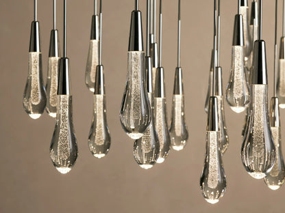 Alt text: Soltaire Round Chandelier with multiple elongated, teardrop-shaped glass bulbs suspended from thin black cords against a neutral background.