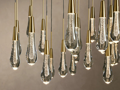 Soltaire Round Chandelier with multiple elongated teardrop-shaped glass pendants, featuring brass-finished tops and visible LED bulbs inside.
