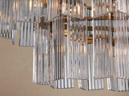 Delsie Oval Tiered Chandelier featuring clear ribbed glass panels, burnished brass frame, suspended on a plain background.