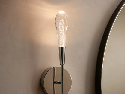 Soltaire Double Sconce with a nickel finish on a round backplate, featuring two elongated clear glass shades extending vertically.