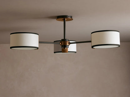 Daphne Flush Mount: 3 white linen shades with black trim, dark bronze frame, lit against a grey ceiling.