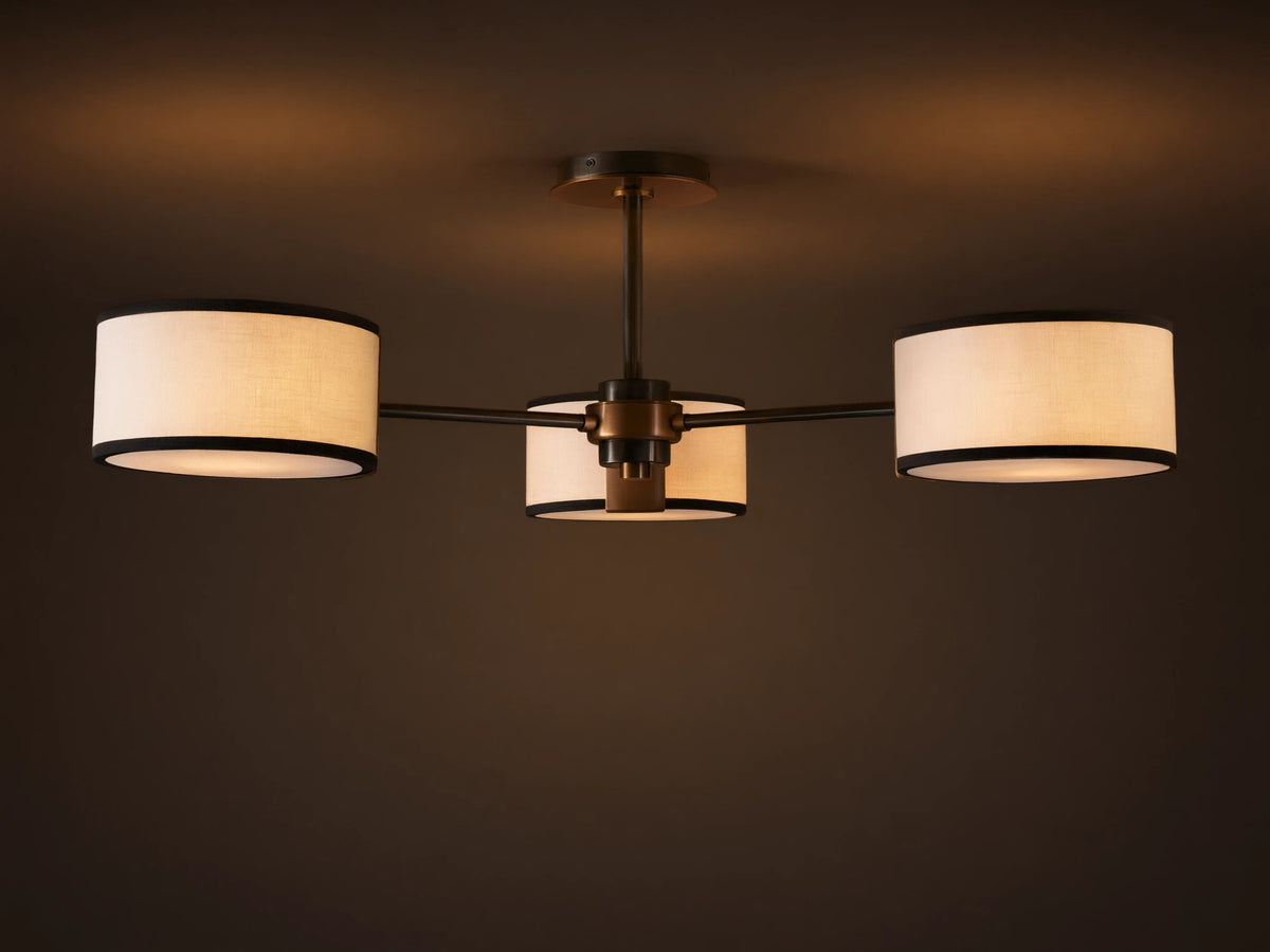 Daphne Flush Mount: 3 white linen shades with black trim, dark bronze frame, lit against a grey ceiling.