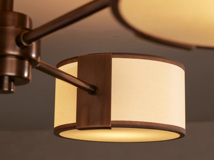 Daphne Flush Mount: Bronze ceiling fixture with three arms, each holding an off-white fabric shade with brown trim.