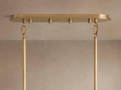 Close-up of Delsie Oval Tiered Chandelier; warm light glows through rows of fluted, textured glass rods & brass frame.