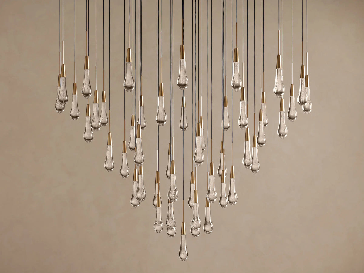 Soltaire Round Chandelier with many clear, textured teardrop-shaped LED bulbs, brass-finished tops, hanging at various lengths.