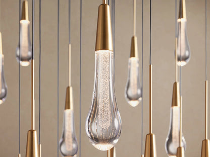 Close-up of Soltaire Round Chandelier with multiple clear teardrop glass lights, brass caps, and internal bubbly texture.