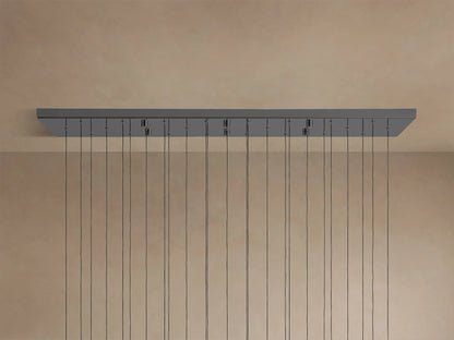 Soltaire Linear Chandelier: Dark gray rectangular ceiling canopy with many thin black cords hanging down against a light beige ceiling.