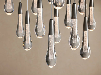 Soltaire Round Chandelier: Clear, bubbly teardrop pendants with dark metallic caps, illuminated against a light background.