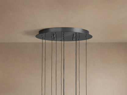 Soltaire Round Chandelier's dark metallic round ceiling canopy with multiple black cords hanging down, against a beige ceiling.