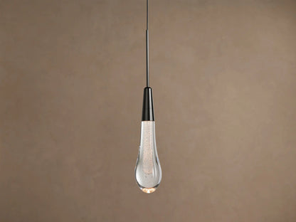 Soltaire Pendant, hanging vertically, with a dark nickel cap and a clear, bubble-filled teardrop glass shade glowing warmly.