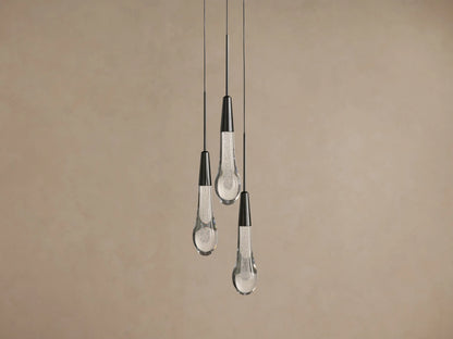 Soltaire Cluster Pendant: Three teardrop-shaped lights with dark metal tops and clear, textured glass bottoms hang from wires.