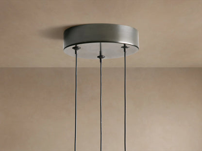 Three Soltaire Cluster Pendants with dark metal tops & teardrop clear glass shades, filled with bubbles & emitting warm light.