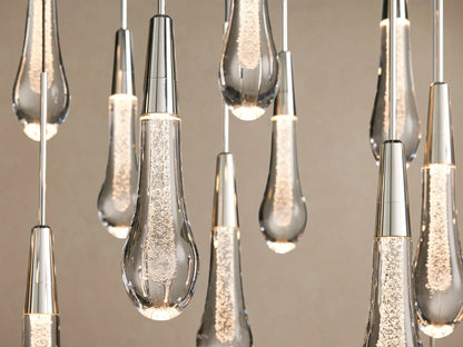 Soltaire Round Chandelier with many clear, sparkling teardrop glass pendants with nickel tops, hanging in a V-shape.