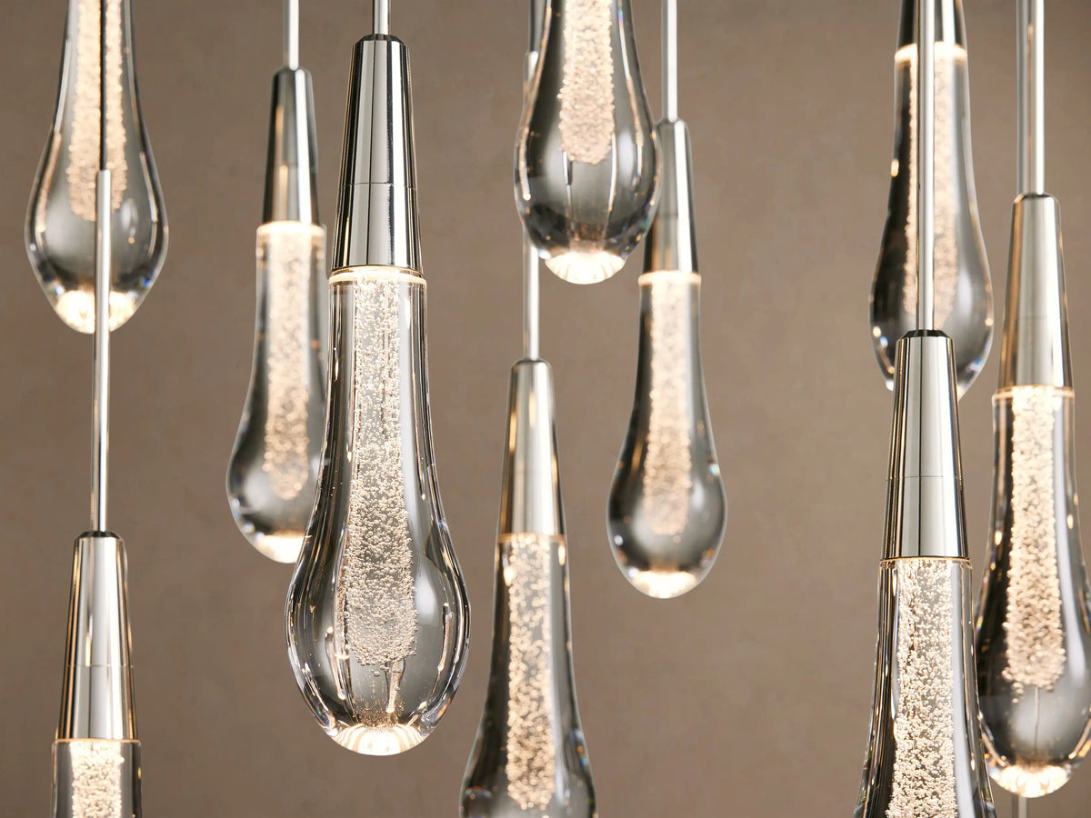 Soltaire Linear Chandelier with many clear, tear-drop shaped glass pendants hanging from thin wires, featuring silver caps & integrated LEDs.