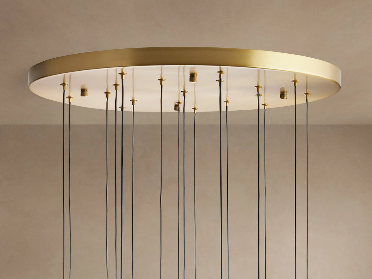 Close-up of Soltaire Round Chandelier. Clear teardrop glass pendants with sparkling LED lights and silver caps against a light brown wall.